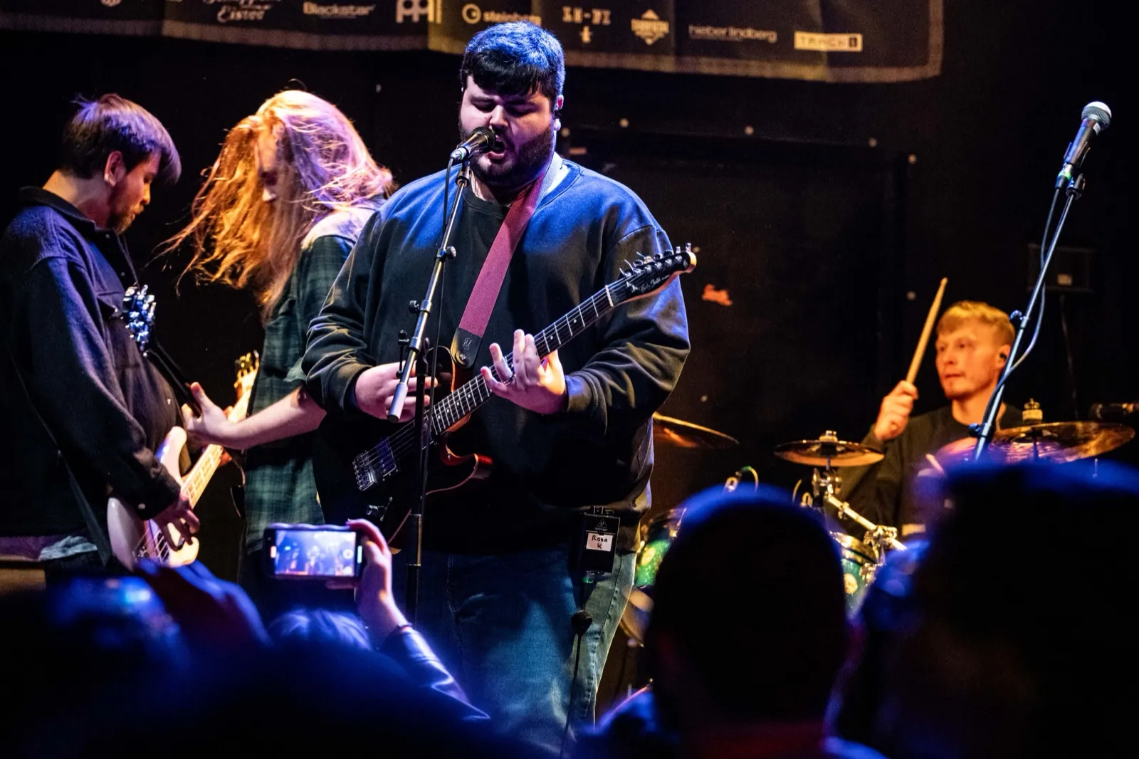 The band on the Backstage Club stage in blue light, phones up in the crowd